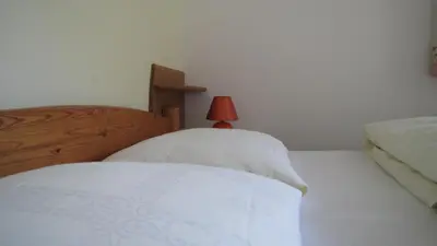 a bedroom with two beds and a red lamp at Blasbichler Appartments in Brunico