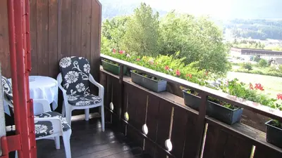 a balcony with two chairs and a table and flowers at Blasbichler Appartments in Brunico