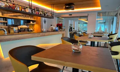 a restaurant with tables and chairs and a bar at Hotel Flora Alpina in Campitello di Fassa