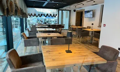 a restaurant with wooden tables and chairs and windows at Hotel Flora Alpina in Campitello di Fassa