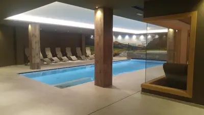 a house with a swimming pool in a room at Hotel Flora Alpina in Campitello di Fassa