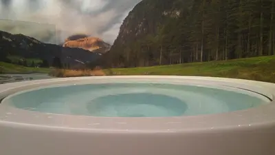 a hot tub with a view of a mountain at Hotel Flora Alpina in Campitello di Fassa