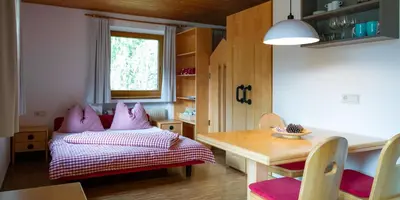 a bedroom with a bed with pink pillows and a table at Residence Veider in Rasùn di Sotto