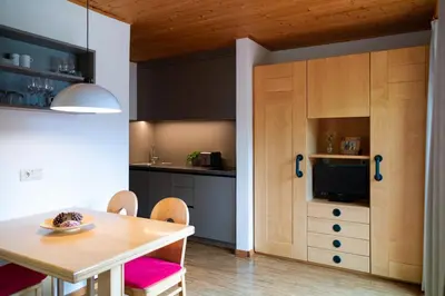 a kitchen with wooden cabinets and a table and chairs at Residence Veider in Rasùn di Sotto