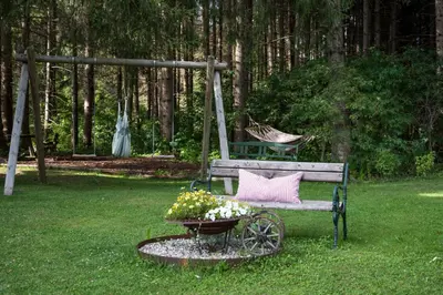 a bench with a pink pillow and a basket of flowers at Residence Veider in Rasùn di Sotto