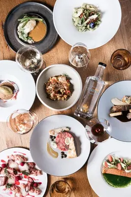 a table with plates of food and glasses of wine at Stadele in Lana