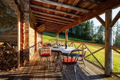 a wooden deck with a table and chairs on it at Berghütte Blockhaus in Redagno