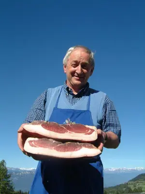 a man is holding a large slab of meat at Berghütte Blockhaus in Redagno