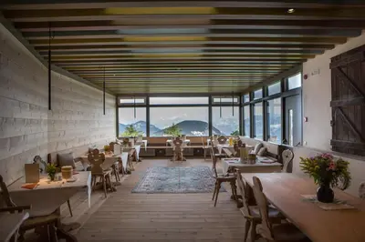 a restaurant with tables and chairs and large windows at Berghütte Blockhaus in Redagno
