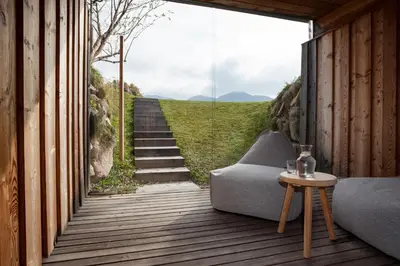 a room with a couch on a wooden deck with a staircase at Berghütte Blockhaus in Redagno