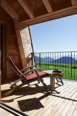 a rocking chair on a porch with a table at Der Zirmerhof in Redagno