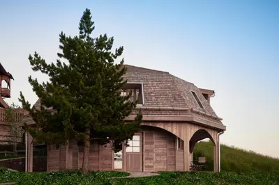 a house with a gambrel roof and a tree at Der Zirmerhof in Redagno