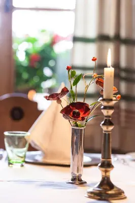 two vases with flowers and a candle on a table at Der Zirmerhof in Redagno