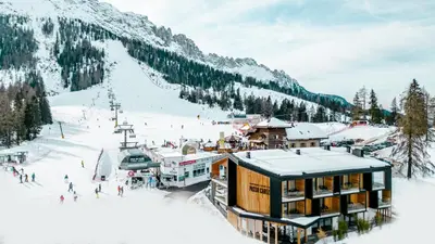 a ski lodge in the snow with a ski slope at Sport Hotel Passo Carezza in Vigo di Fassa