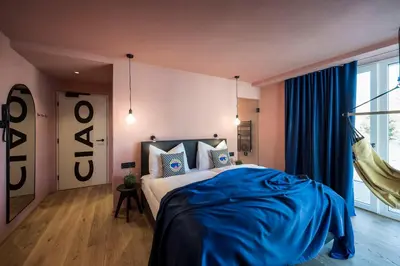 a bedroom with a bed with blue sheets and a window at Sport Hotel Passo Carezza in Vigo di Fassa