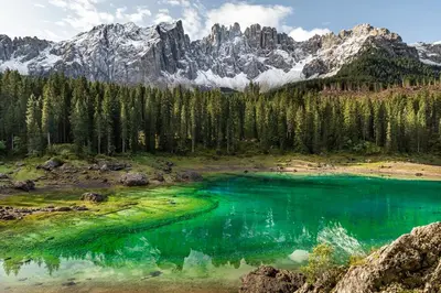 a mountain lake with turquoise water and trees at Sport Hotel Passo Carezza in Vigo di Fassa