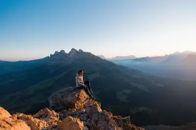 a person sitting on top of a mountain at Sport Hotel Passo Carezza in Vigo di Fassa