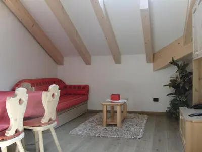 a living room with a red couch and two chairs at Residence Garni Manuela in Cavalese