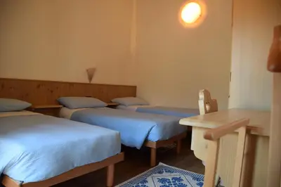 a room with four beds and a table and a desk at Residence Garni Manuela in Cavalese