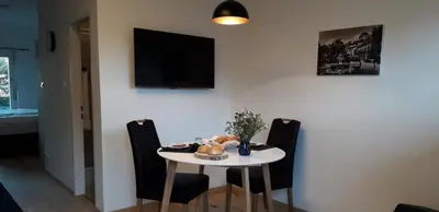 a white table with chairs and a television on a wall at Apartment Hagen in Merano