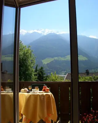 a table with a view of a mountain from a window at Alpina Residence in Naturno