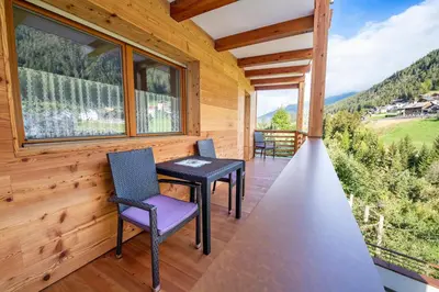 a porch with two chairs and a table and windows at Apartments La Rives in Santa Cristina in Val Gardena