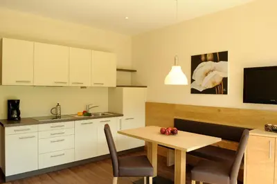 a kitchen with white cabinets and a table and a television at Apartment Hotel Christine in Avelengo
