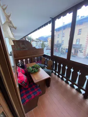 a balcony with a table and a bench and a window at Incantevole monolocale in centro a Cortina. in Cortina dʼAmpezzo