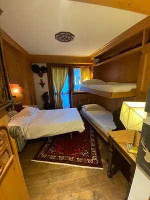 a bedroom with two bunk beds and a table at Incantevole monolocale in centro a Cortina. in Cortina dʼAmpezzo