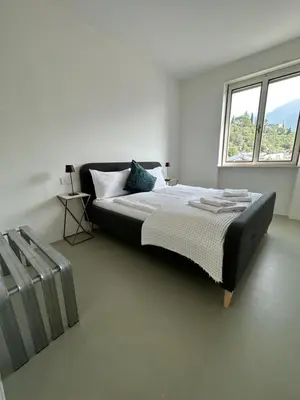 a white bedroom with a large bed and a window at Merano Absolute View in Merano