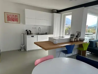 a kitchen with white cabinets and a table and chairs at Merano Absolute View in Merano