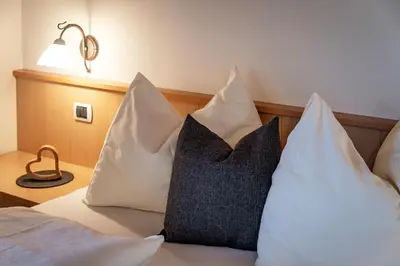 a bed with white pillows and a black and white pillow at Trinnerhof- Hof Chalets und Obsthof in Naz-Sciaves