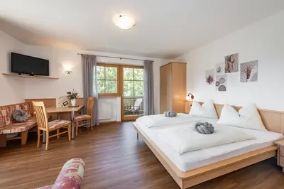 a bedroom with a large bed and a dining room at Trinnerhof- Hof Chalets und Obsthof in Naz-Sciaves