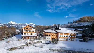 a house in the snow with mountains in the background at Trinnerhof- Hof Chalets und Obsthof in Naz-Sciaves