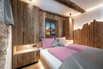 a bedroom with wooden walls and a bed with pink pillows at Oberkantiolhof in Villnoss