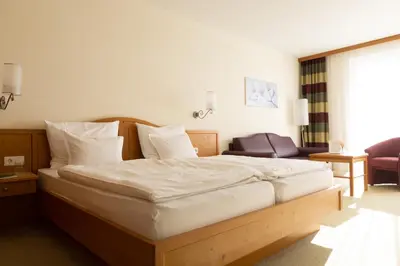 a bedroom with a large bed with white sheets at Garni Kleefeld in Schenna