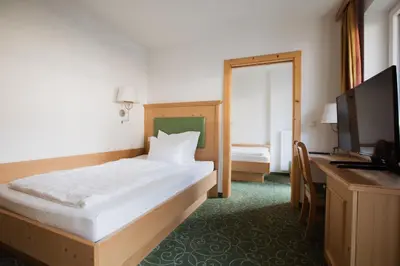 a bedroom with a bed and a desk and a television at Garni Kleefeld in Schenna