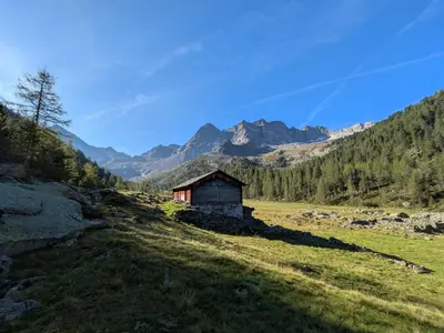 an old barn in a field with mountains in the background at Residence Aichner in Brunico