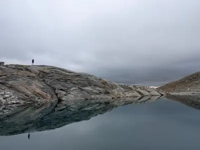a person standing on top of a rock over water at Residence Aichner in Brunico