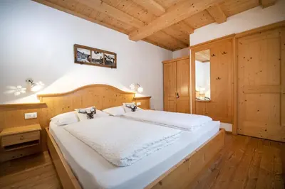 a bedroom with a large white bed with a wooden headboard at Apartments Bea in Ortisei