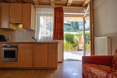a kitchen with wooden cabinets and a sliding glass door at Apartments Bea in Ortisei