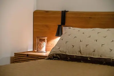 a bed with a wooden headboard with a candle on a night stand at Charming Civetta in Alleghe