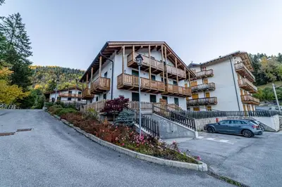 a large building with a car parked in a parking lot at Charming Civetta in Alleghe