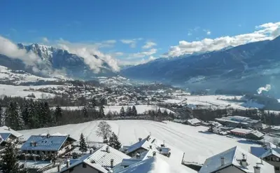 a town covered in snow with mountains in the background at Pozza Appartamenti in Carano