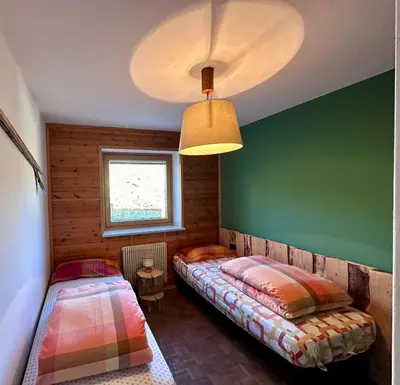 two beds in a room with a green wall at Pozza Appartamenti in Carano