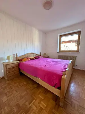 a bedroom with a large bed with a pink blanket at Pozza Appartamenti in Carano