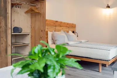 a bedroom with a bed with white sheets and a plant at Agritur E-Cinque in Salorno sulla Strada del Vino