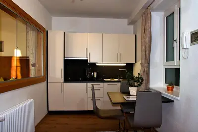 a kitchen with white cabinets and a table with chairs at Gasthaus Babsi in Soprabolzano