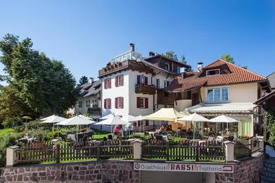 a building with tables and umbrellas in front of it at Gasthaus Babsi in Soprabolzano