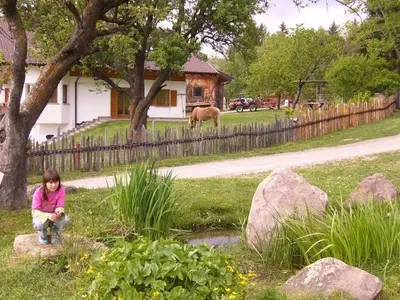 a little girl sitting in the grass near a pond at Gastreinhof in Meltina